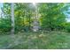 Backyard featuring a wooden playhouse with slide and swingset nestled among the trees at 6417 Loyola Ct, Mint Hill, NC 28227