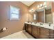 Well-lit bathroom featuring double sinks, a large mirror, tile flooring, and warm wall tones at 6417 Loyola Ct, Mint Hill, NC 28227