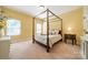 Yellow bedroom featuring a wooden canopy bed, soft carpet, and natural light from the windows at 6417 Loyola Ct, Mint Hill, NC 28227
