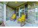 Cozy front porch with stone accents and two rocking chairs with bright yellow cushions at 6417 Loyola Ct, Mint Hill, NC 28227