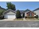 Charming single-story home with a well-manicured lawn and a cozy red front door, complemented by a two-car garage at 8655 Meadowmont View Dr, Charlotte, NC 28269