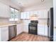 Well-lit kitchen featuring white cabinets, stainless steel appliances, and wood-look flooring at 8655 Meadowmont View Dr, Charlotte, NC 28269