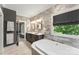 Bathroom with double vanity, soaking tub, tile accent walls, and wood-look tile flooring at 10007 Hillspring Dr, Huntersville, NC 28078