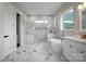 Bright, elegant bathroom featuring marble-tiled walls and floors, a modern soaking tub, and a glass-enclosed shower at 106 Kelly Marie Ct, Kings Mountain, NC 28086