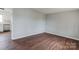 Empty room featuring new hardwood floors and neutral walls, with view of kitchen at 120 Tower Dr, Statesville, NC 28677