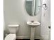 Well-lit half bathroom featuring a pedestal sink, round mirror, and tiled flooring at 12421 Fiorentina St, Charlotte, NC 28277