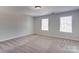 An empty bedroom features neutral carpet and two windows that let in natural light at 1325 Grantwood Nw Ave, Concord, NC 28027