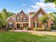 Charming brick home featuring lush landscaping, a manicured lawn, and a welcoming front porch at 15009 Fanning Manor Ct, Charlotte, NC 28277