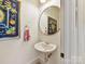 Chic powder room with a round mirror, pedestal sink, and decorative hand towel at 15009 Fanning Manor Ct, Charlotte, NC 28277