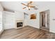 Open living room with hardwood floors, fireplace, built-in shelving, ceiling fan, and view into the kitchen at 17431 Tuscany Ln, Cornelius, NC 28031