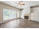 Bright living room with wood floors, fireplace, built-in shelving, large windows, and a ceiling fan at 17431 Tuscany Ln, Cornelius, NC 28031