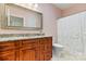 Bathroom with granite countertop, wood cabinets, decorative mirror and shower with white floral curtain at 2369 Stardust Ct, Denver, NC 28037