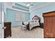 Comfortable bedroom with tray ceiling, ceiling fan, plush carpeting, and a decorative wooden bed frame at 2369 Stardust Ct, Denver, NC 28037