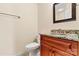 Stylish half-bathroom with a granite countertop, dark wood cabinets, and a classic toilet and mirror at 2369 Stardust Ct, Denver, NC 28037
