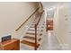 Elegant staircase featuring wood treads, white risers, and railing leading to a hallway with view into updated kitchen at 2369 Stardust Ct, Denver, NC 28037