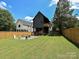 Large backyard with a fire pit, a wooden fence, and two-story modern home in the background at 2553 Elkwood Cir, Charlotte, NC 28205