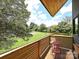 Outdoor balcony with wood floors and railings, a small table with chairs, and views of the lush backyard at 2553 Elkwood Cir, Charlotte, NC 28205
