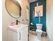 Chic half bath features blue tiled wall, modern white vanity, round mirror, and hexagon tile floors at 2553 Elkwood Cir, Charlotte, NC 28205