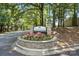 Stone Heathstead condominium community sign framed by colorful flowers and mature trees at 3020 Heathstead Pl # A, Charlotte, NC 28210