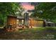 Backyard view of a house with patio, stone chimney, and gazebo in a wooded setting at sunset at 407 Sweetgum Dr # B, Fort Mill, SC 29715