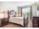 Comfortable bedroom featuring a queen-sized bed, dark wood furniture, and a view to the outside at 4116 Tory Path Rd, Waxhaw, NC 28173