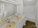 Bathroom with double sink vanity, white cabinets, a large mirror, and a shower/tub combo at 424 Mallard Dr, Pineville, NC 28134