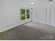 Spacious bedroom with soft gray carpet, closet space, and view of mature trees at 424 Mallard Dr, Pineville, NC 28134
