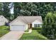 Charming single-story home featuring a well-manicured lawn, attached garage, and lush, mature trees in a tranquil setting at 5221 Javitz Rd, Charlotte, NC 28216