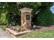 Auburn Place stone monument entrance sign complemented by flowering plants and American flags at 8409 Darcy Hopkins Dr, Charlotte, NC 28277