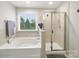 Bright bathroom featuring a soaking tub, glass shower, and a window offering outdoor views at 9450 Surface Hill Rd, Mint Hill, NC 28227