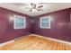 A bedroom with hardwood floors, purple walls, two windows, and a ceiling fan offers bright natural light at 1132 Arbor Dr, Salisbury, NC 28144