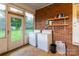 Laundry area with washer, dryer, and shelves, set against a charming brick wall at 1132 Arbor Dr, Salisbury, NC 28144