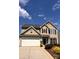 Charming two-story home featuring beige siding, a two-car garage, and a well-manicured front yard on a sunny day at 115 Morrocroft Ln, Mooresville, NC 28117