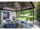 Relaxing covered patio featuring comfortable seating, decorative pillows, and a view of the backyard at 115 Morrocroft Ln, Mooresville, NC 28117
