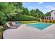 Spacious backyard featuring an in-ground pool, mature trees, lounge chairs, and well-manicured lawn at 12416 Stirling Trace Ct, Charlotte, NC 28277