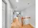 Well-lit hallway with hardwood floors and white walls, leading to bedrooms and a staircase at 12416 Stirling Trace Ct, Charlotte, NC 28277