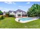 Well-maintained in-ground pool and lush backyard featuring a fire pit, mature trees and grassy area at 12416 Stirling Trace Ct, Charlotte, NC 28277