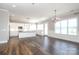 An open-concept kitchen and dining area with dark wood floors and stainless steel appliances and white cabinets at 14019 Cameryn Elise Dr, Cornelius, NC 28031