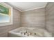 Enjoy a relaxing bath in this luxurious tub, surrounded by sleek tile and bright natural light at 201 Valley St, Stanley, NC 28164