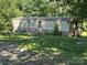 Exterior view of a mobile home, featuring a weathered facade, surrounded by tall, verdant foliage at 208/210 Damascus Rd, Gastonia, NC 28056