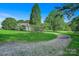 Scenic view of a well-maintained home with mature trees, a gravel driveway, and lush green lawn at 2417 Statesville Blvd, Salisbury, NC 28147