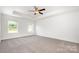 Large main bedroom with tray ceiling, ceiling fan, two windows, and neutral carpet at 3001 Sadler Woods Ln, Charlotte, NC 28214