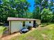 Backyard featuring a ranch-style home with a small deck, steps, and an AC unit surrounded by mature trees at 325 Scaley Bark Dr, Salisbury, NC 28147