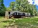 Charming ranch-style home with black trim, inviting deck and ramp access on a lush, tree-lined lot at 325 Scaley Bark Dr, Salisbury, NC 28147
