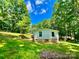 A ranch-style home surrounded by a lush green yard and tall, mature trees on a bright, sunny day at 325 Scaley Bark Dr, Salisbury, NC 28147