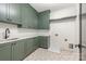 Well-lit laundry room features sleek green cabinets and modern hardware, offering a stylish and functional space at 412 Jefferson Dr, Charlotte, NC 28270