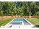 Serene backyard featuring a modern pool with a built-in spa, surrounded by lush greenery and a manicured lawn at 412 Jefferson Dr, Charlotte, NC 28270