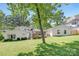 Beautiful backyard view of white painted brick home with deck, lush lawn and mature trees at 5611 Robinhood Rd, Charlotte, NC 28211