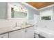 Bright bathroom with a double sink vanity, tub with white tile, and a wood plank ceiling at 5611 Robinhood Rd, Charlotte, NC 28211