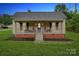 Cozy home with a front porch featuring seating, a brick foundation, and manicured landscaping at 626 Cabarrus W Ave, Concord, NC 28027